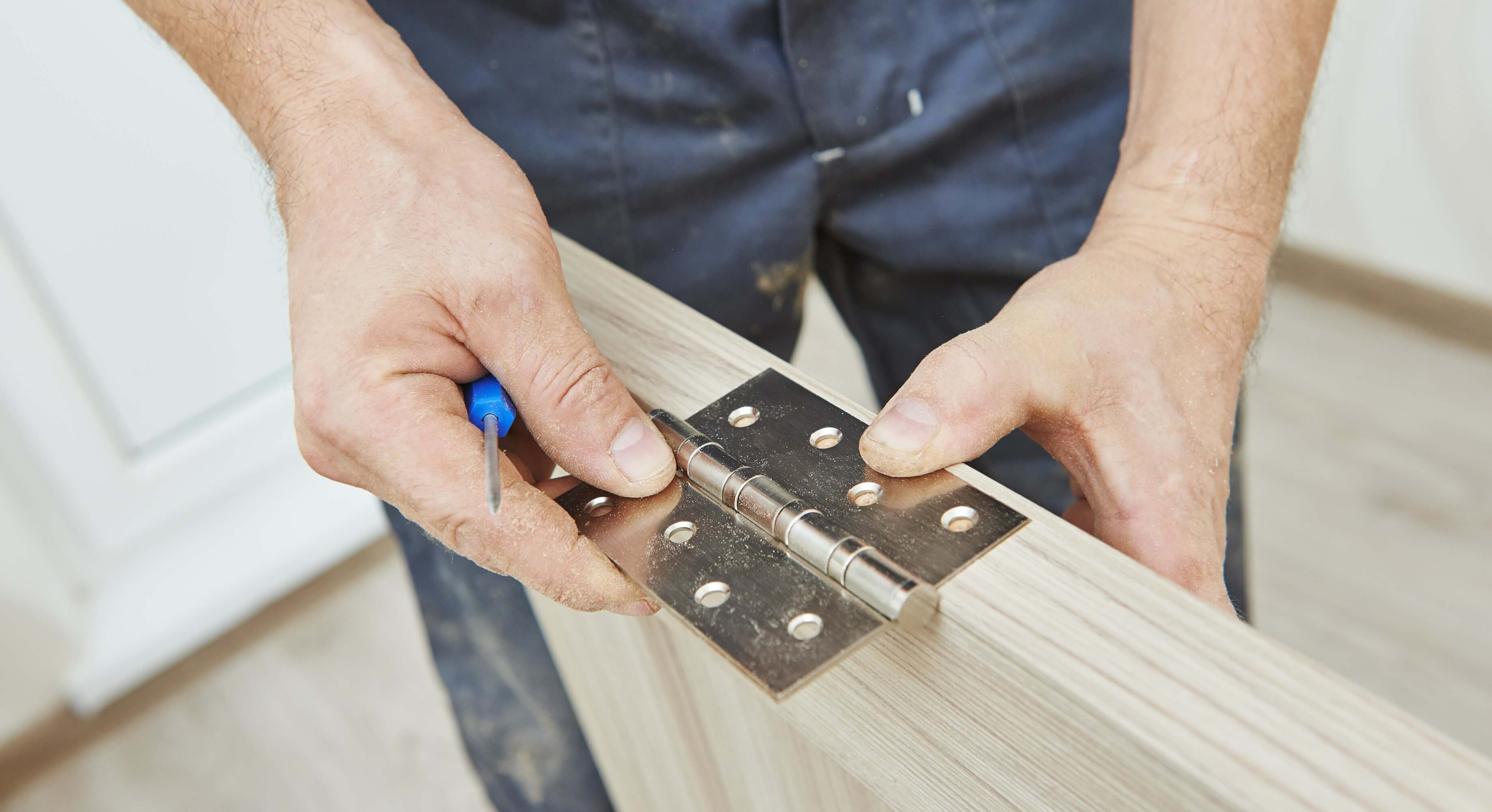 A young man installing a door into a door and door jamb